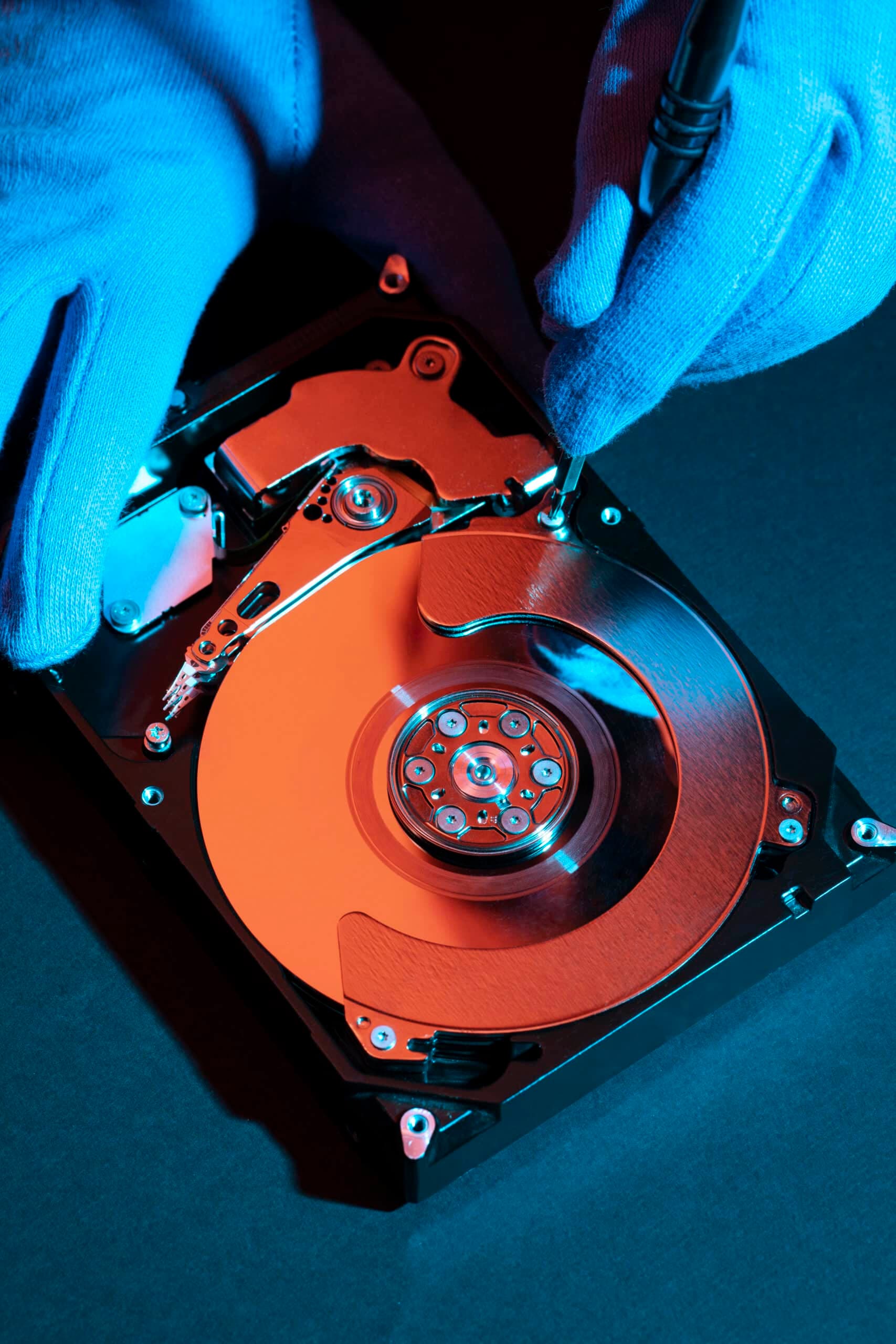 Gloved hands examining a hard drive in a digital forensics laboratory
